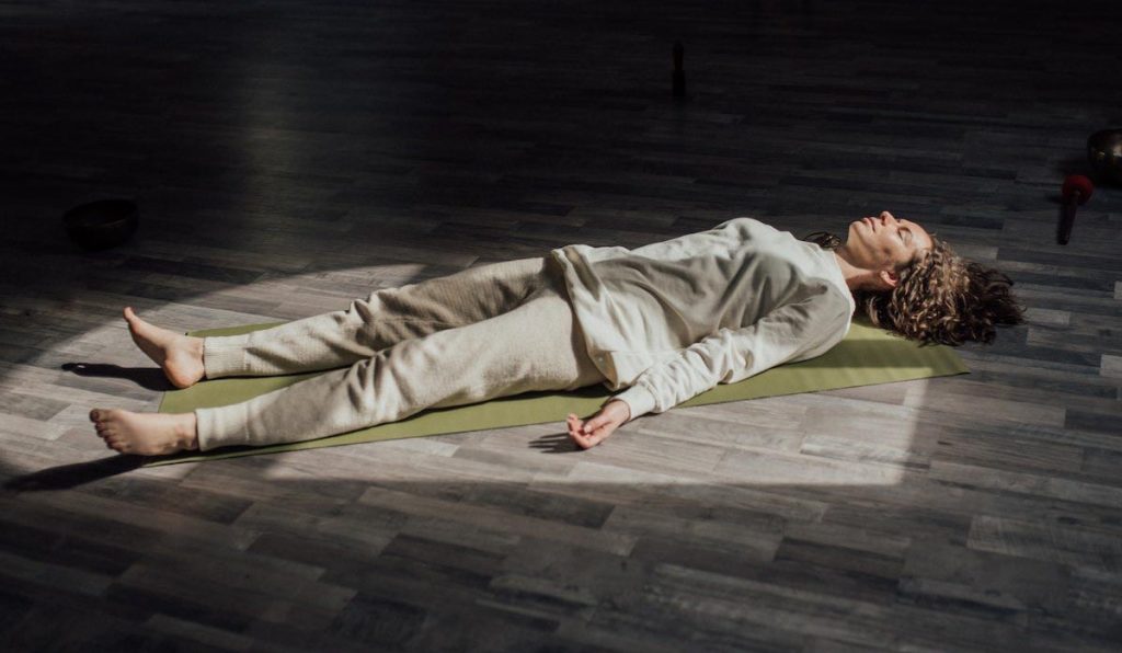 Mujer tumbada en esterilla haciendo yoga nidra