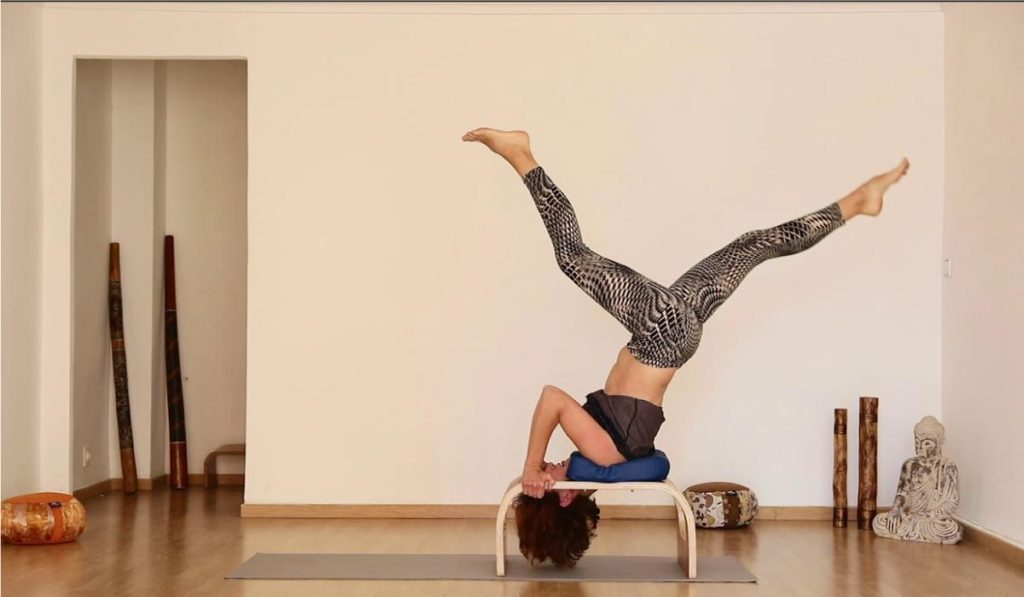 Mujer utilizando bancos de yoga para invertidas