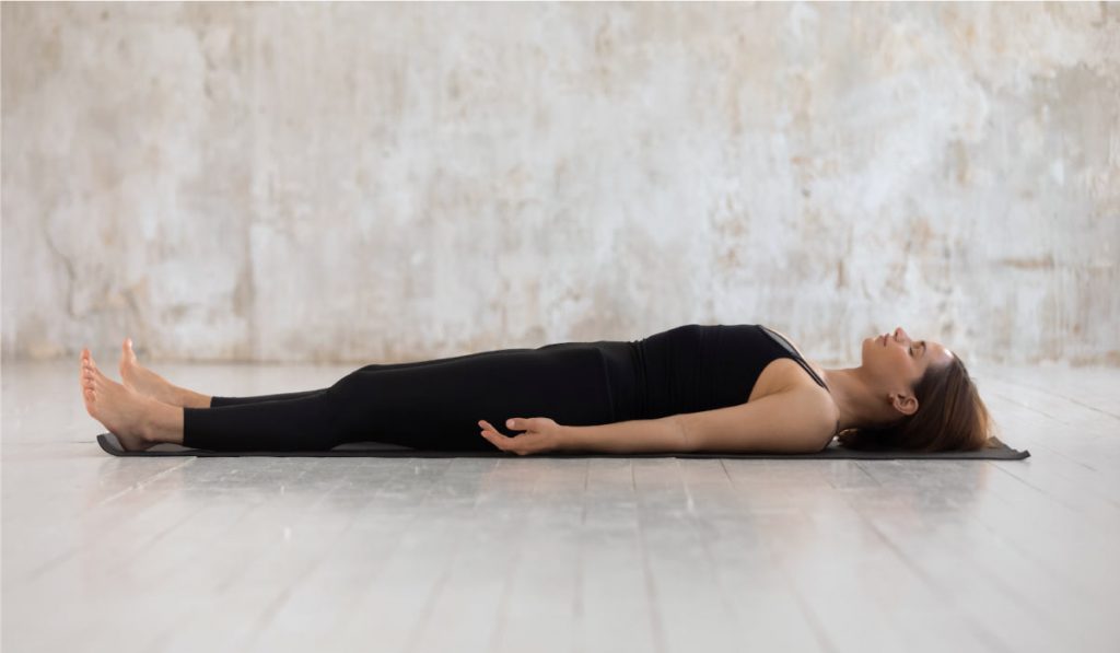 Mujer tumbada en savasana para hacer yoga nidra